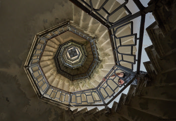 Volta tower spiral staircase This architectural photograph showcases the spiral staircase inside the Volta Tower in Como, Italy. The image captures the staircase from a ground-up perspective, revealing its geometric and decorative railings that create a striking pattern as they ascend toward the top of the tower. Taken in the afternoon during the early autumn season, the photograph highlights the interplay of natural light streaming in from above, illuminating the stairwell’s textured surfaces. The Volta Tower itself serves as a recognizable landmark in Como, and the spiral staircase is a notable feature within this historic Italian structure.